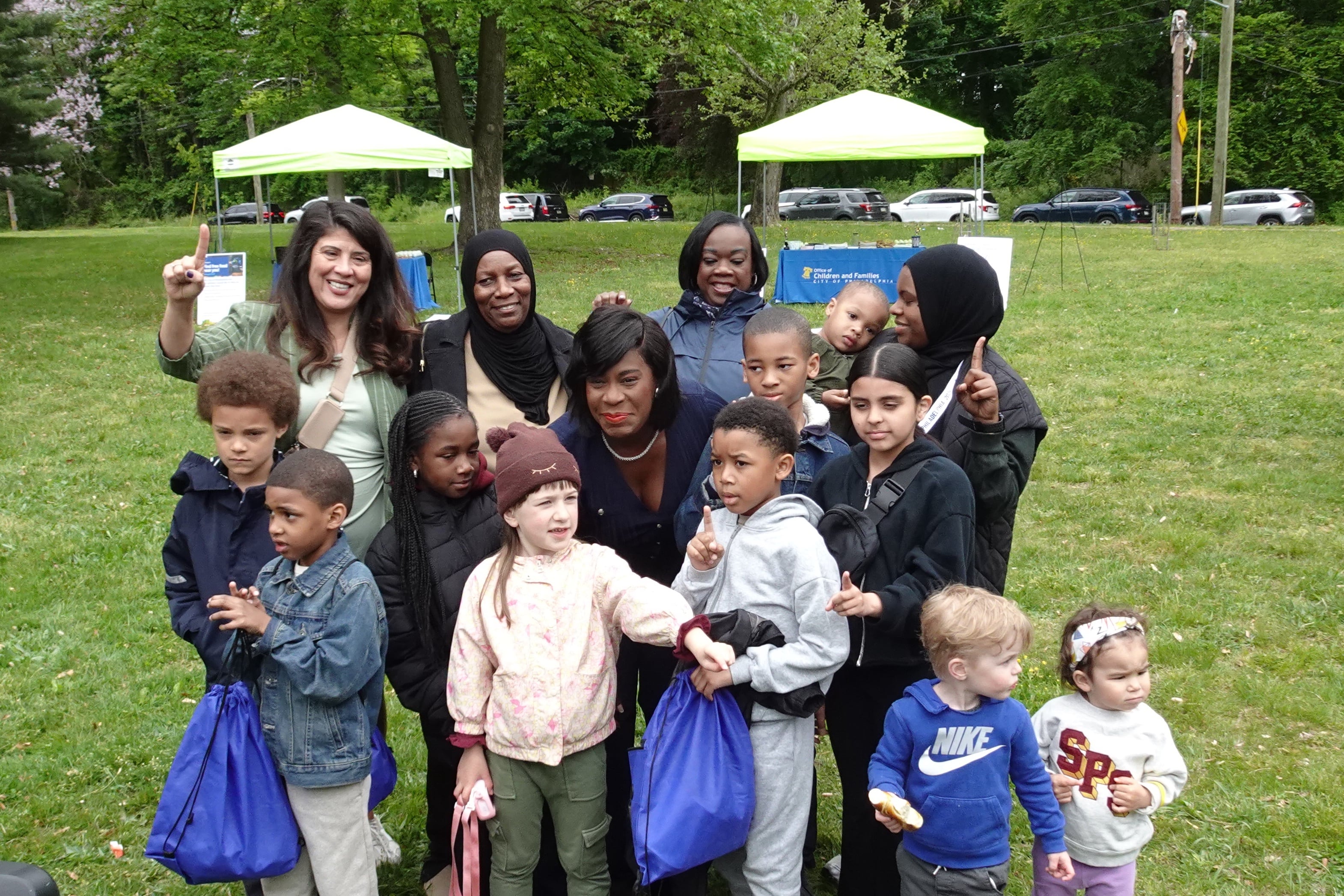 Philadelphia Mayor Cherelle Parker smiles surrounded by a group of young kids and parents in the rain in a park.