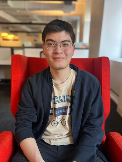 A high school student poses for a portrait on a red chair.