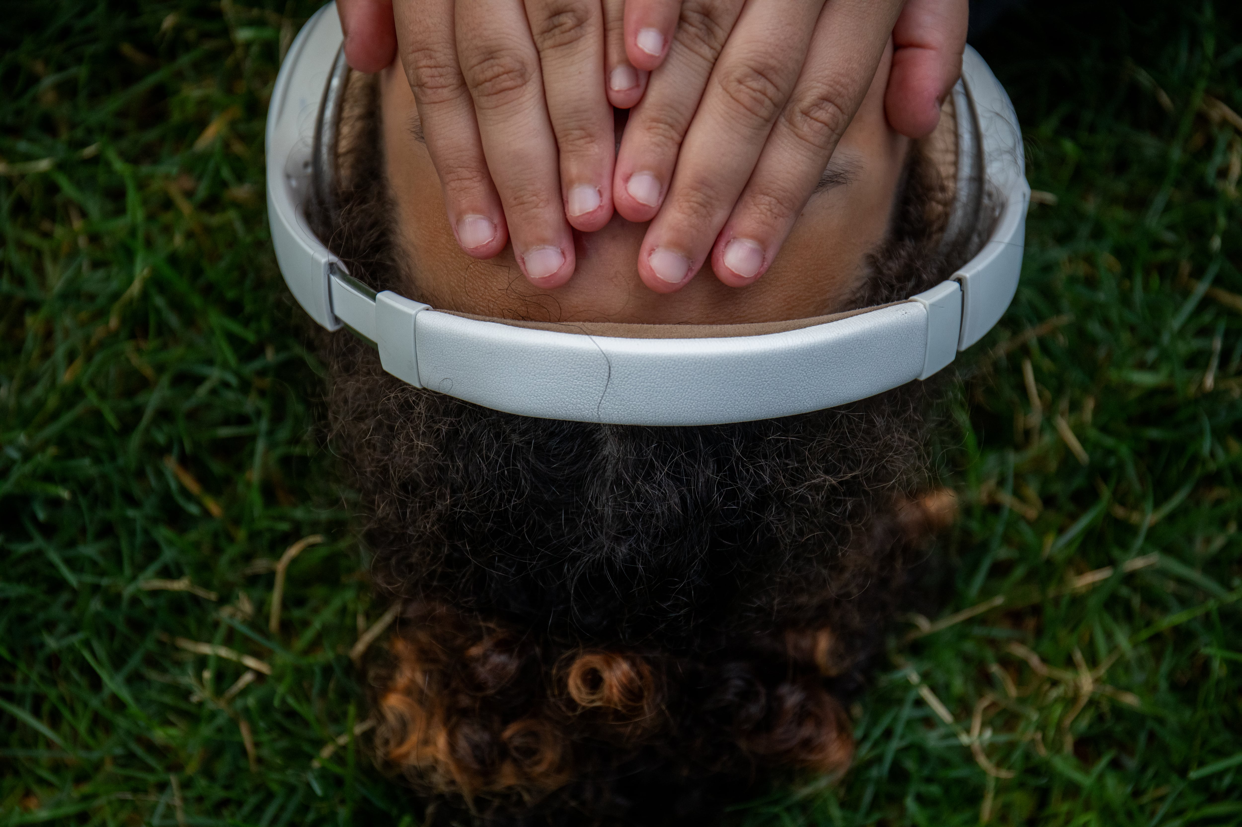 A teen wearing headphones and hands over their face.