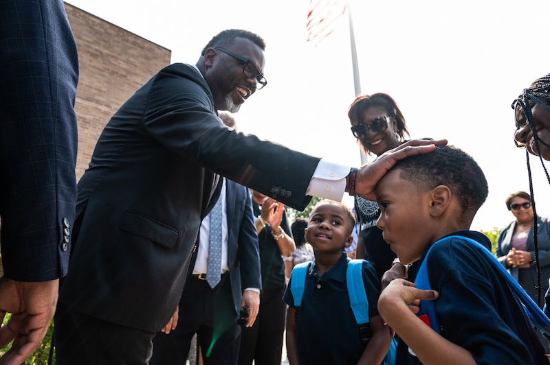 Chicago Mayor Brandon Johnson pats a students head.