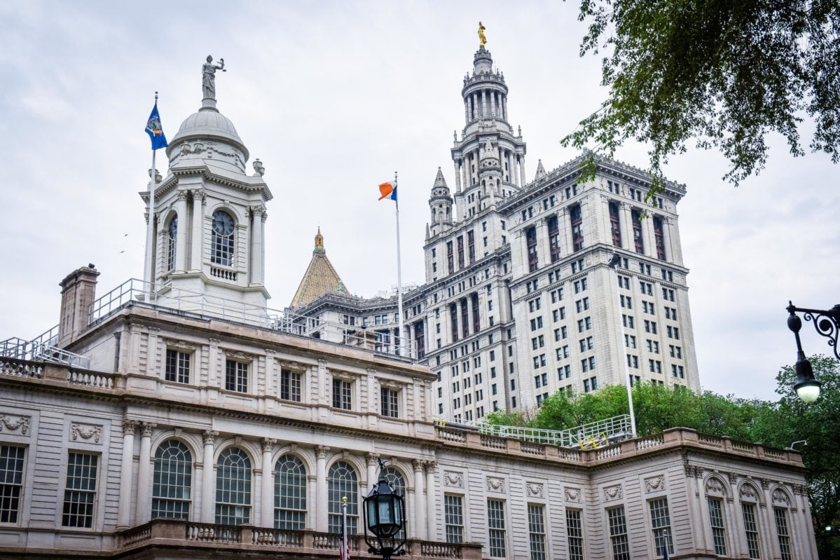 The tops of tall stone buildings with a blue sky in the background.