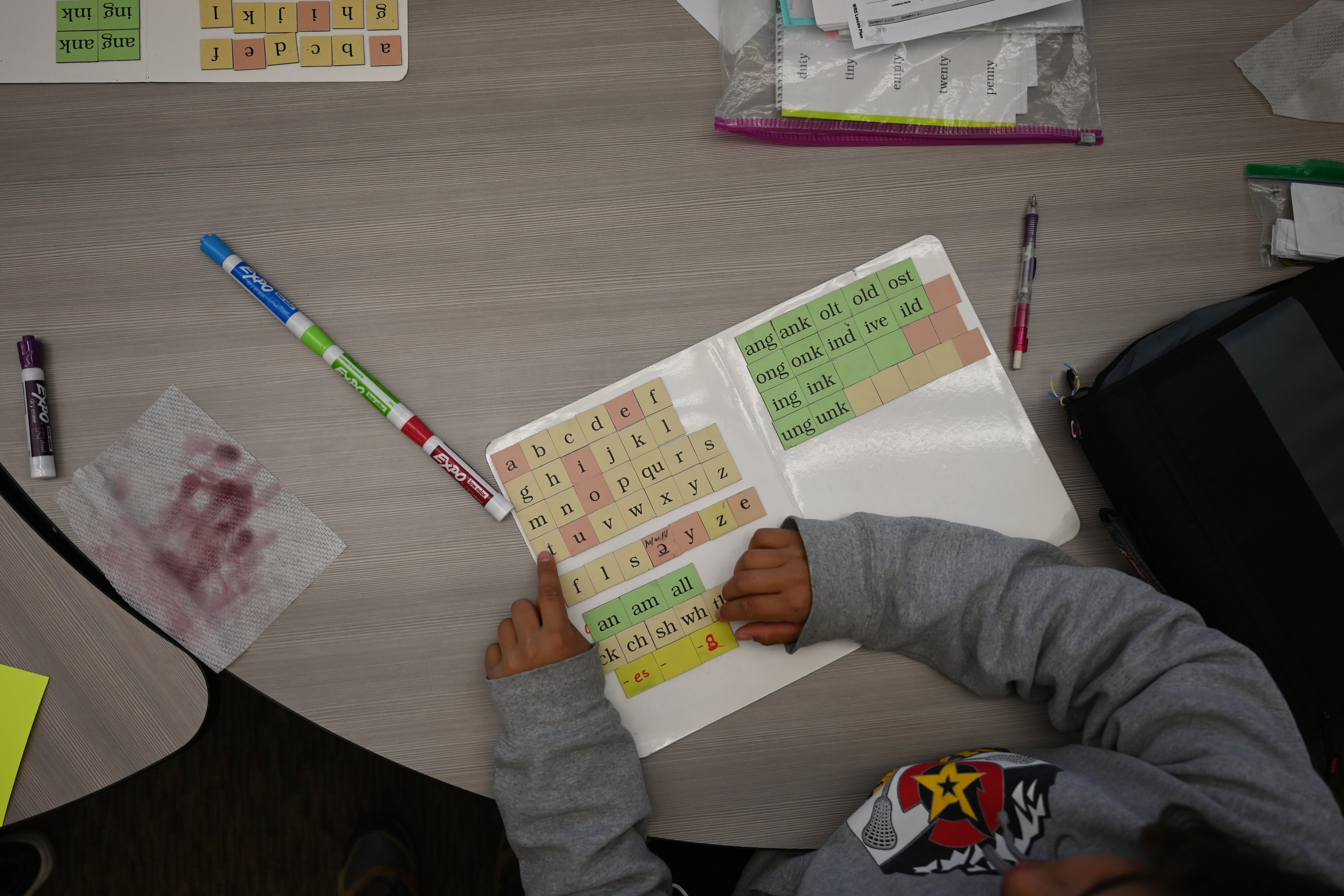 A student works on letter sounds, using a board with magnetic letters at a circular table.