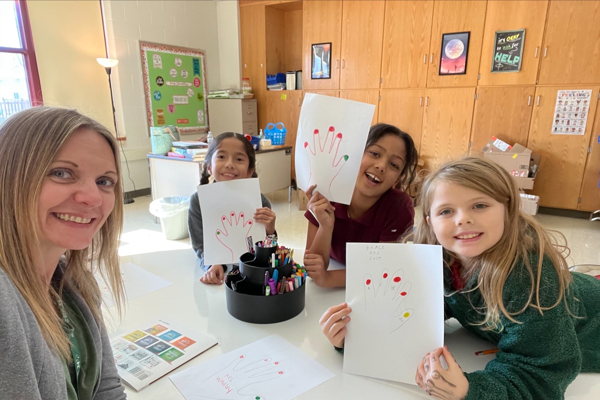 A woman with three kids smile holding projects