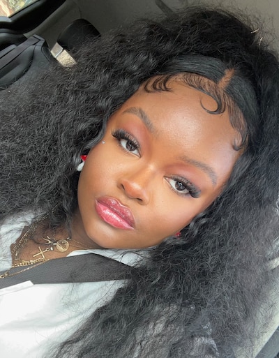 Headshot of a teenage girl with black hair, wearing a white shirt and gold jewelry.