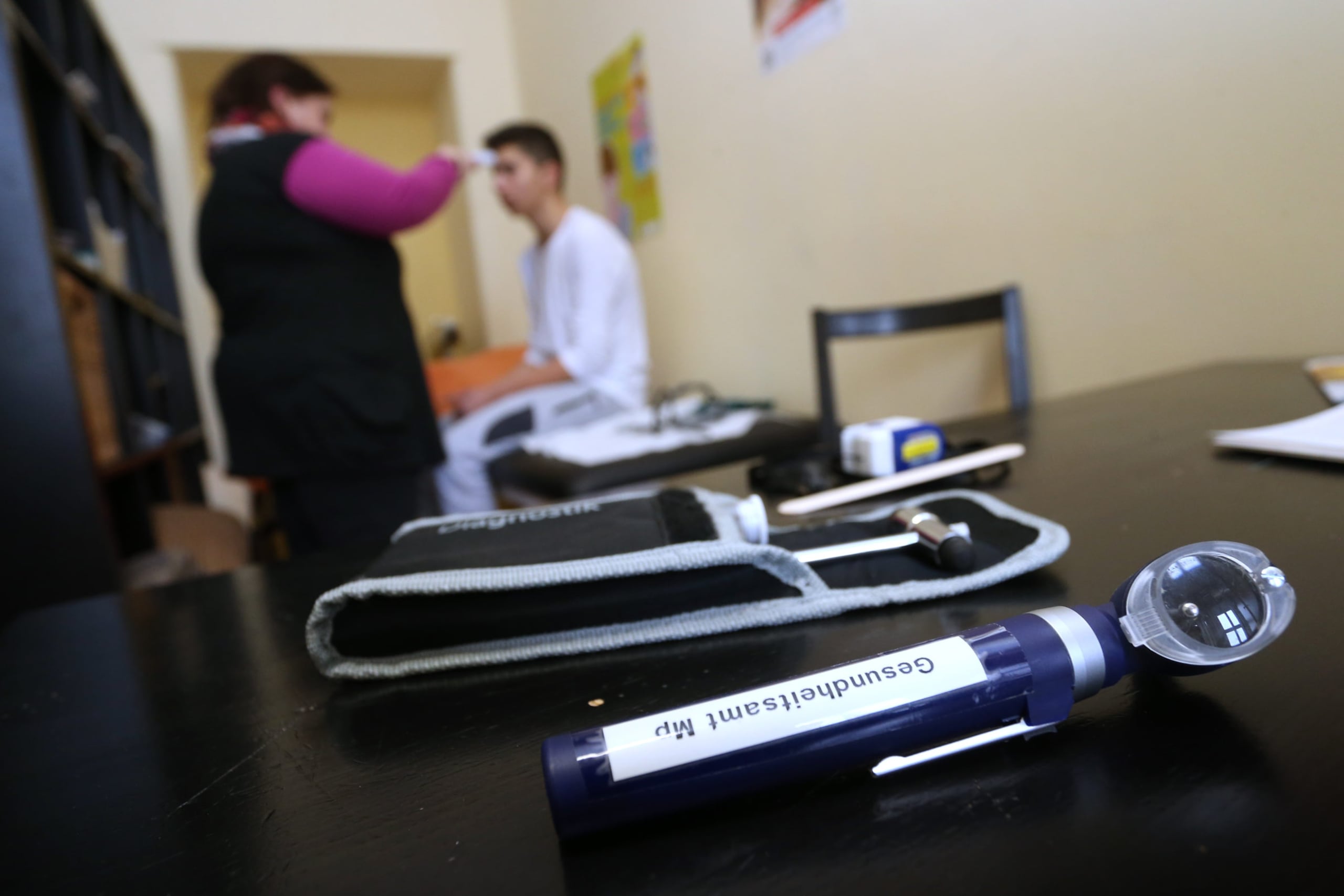 A school nurse and a student sit in the background while tools are seen in the foreground.