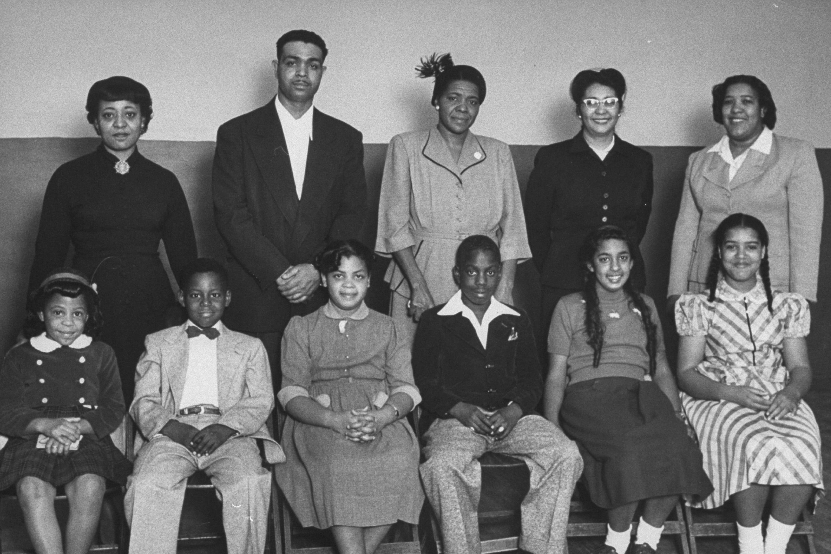 A black and white photo of eleven people wearing business clothes pose for a group portrait.