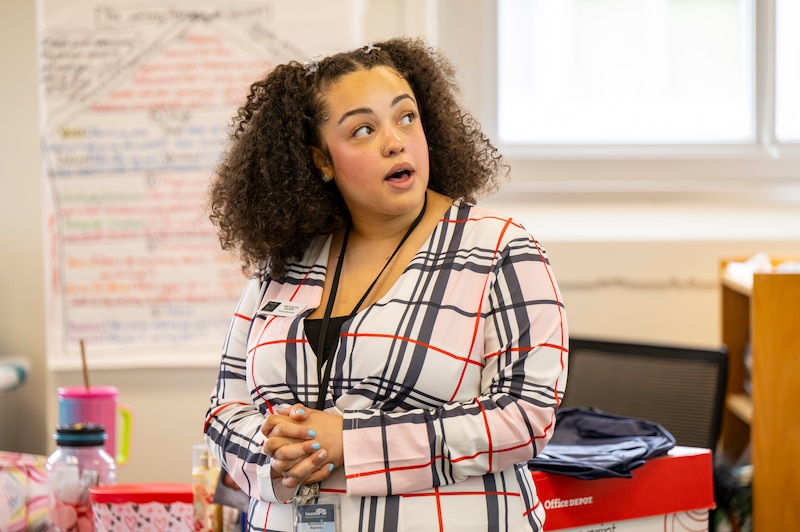 A woman in a plaid jacket stands and talks