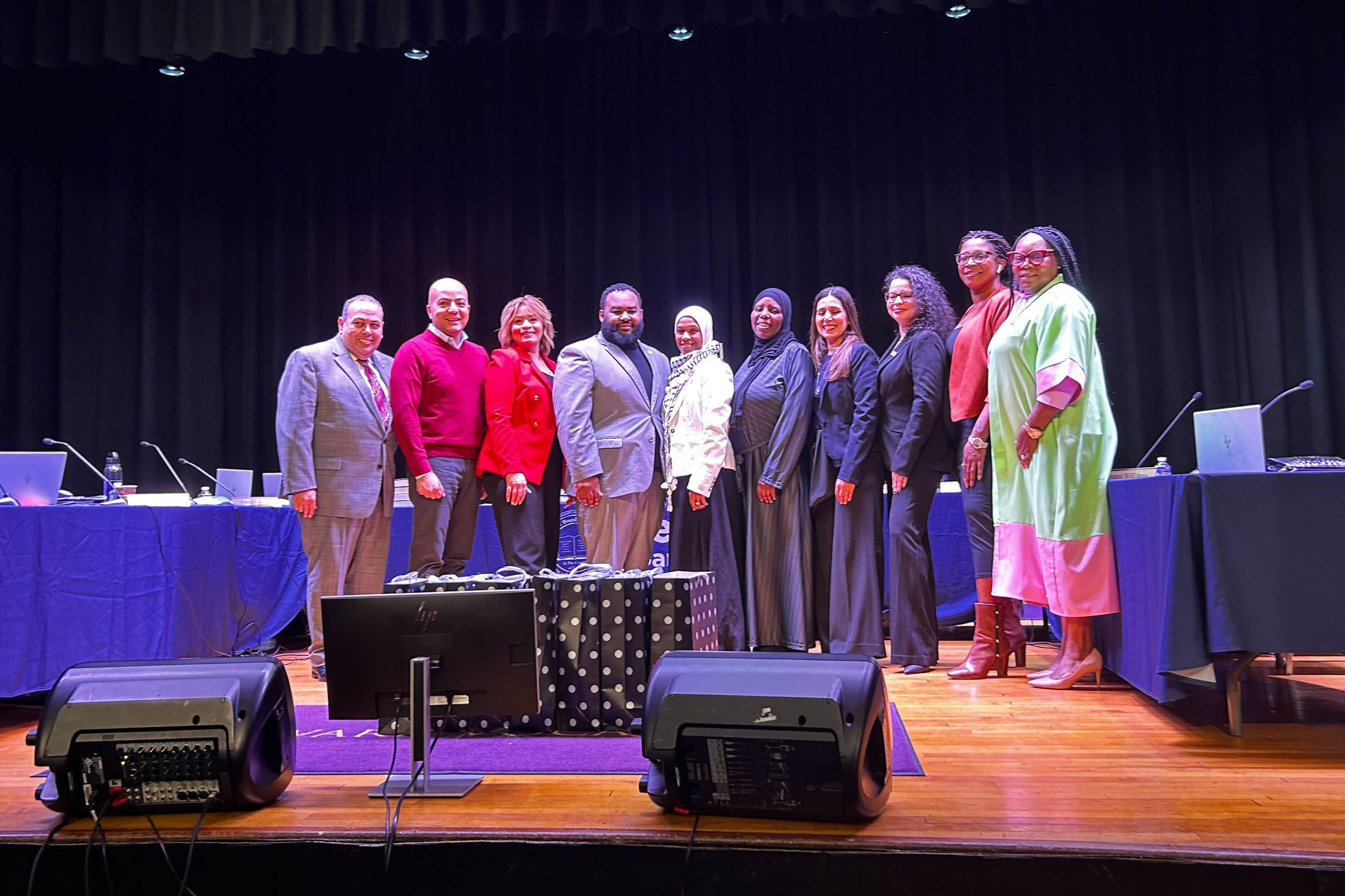 People stand on a stage with tables in the background.